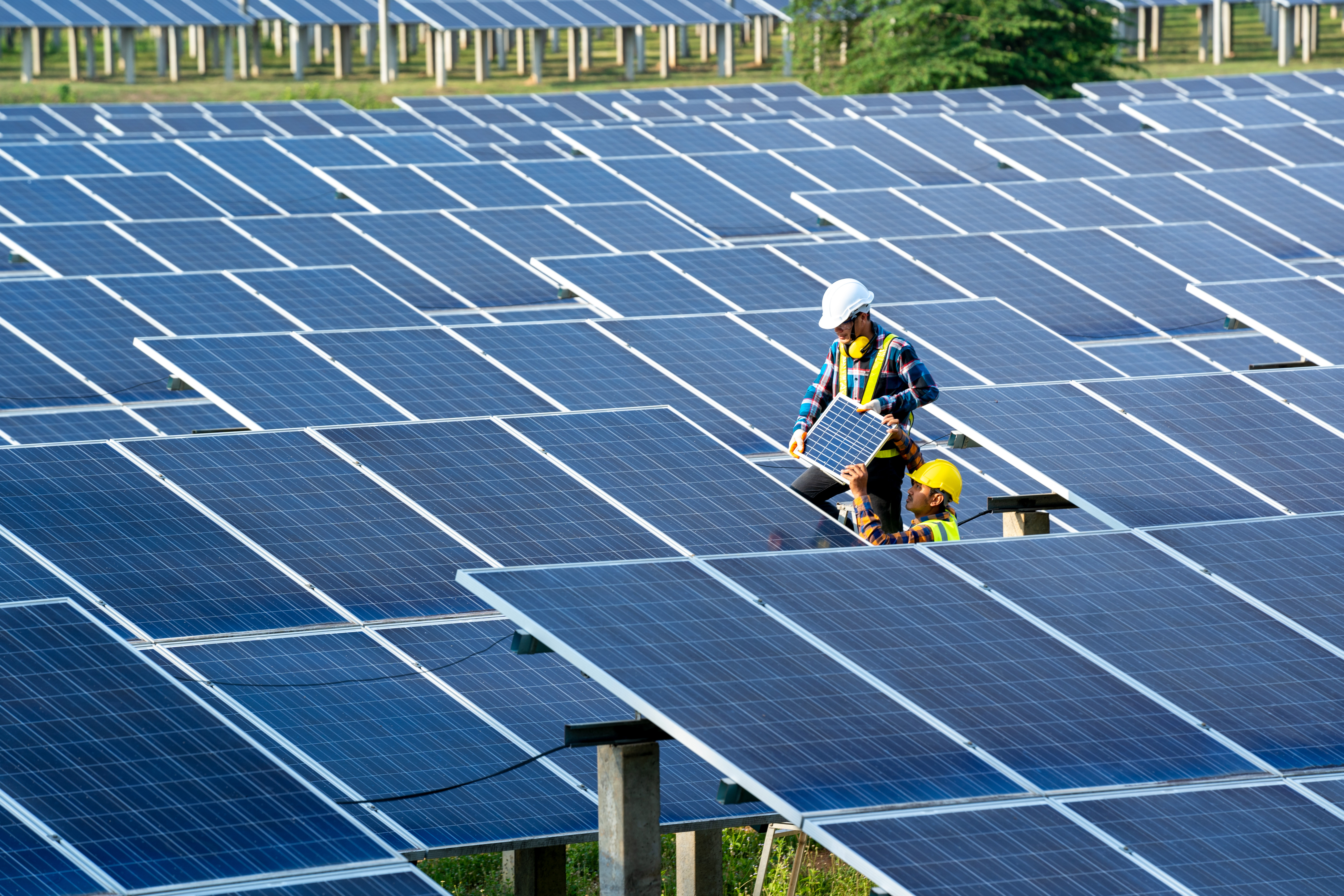 Group of engineer working on checking and maintenance with solar batteries near solar panels at sunny day in solar power plant station.