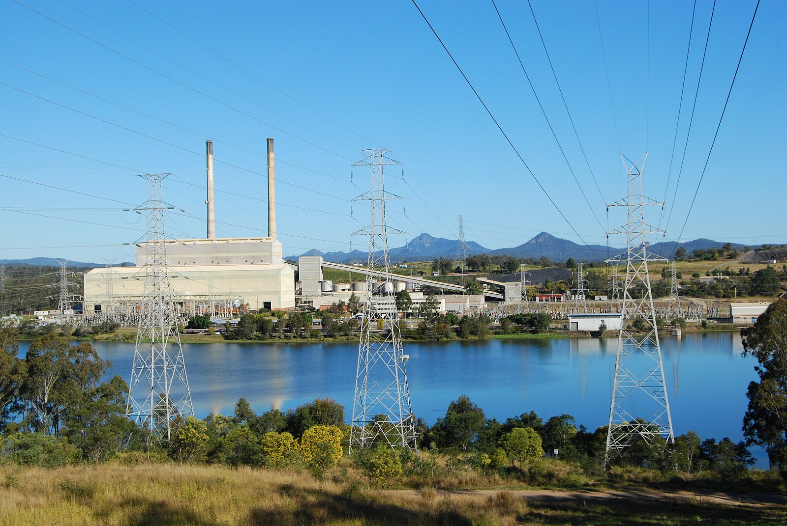 long shot of Swanbank Power Station across a river with 3 transmission towers