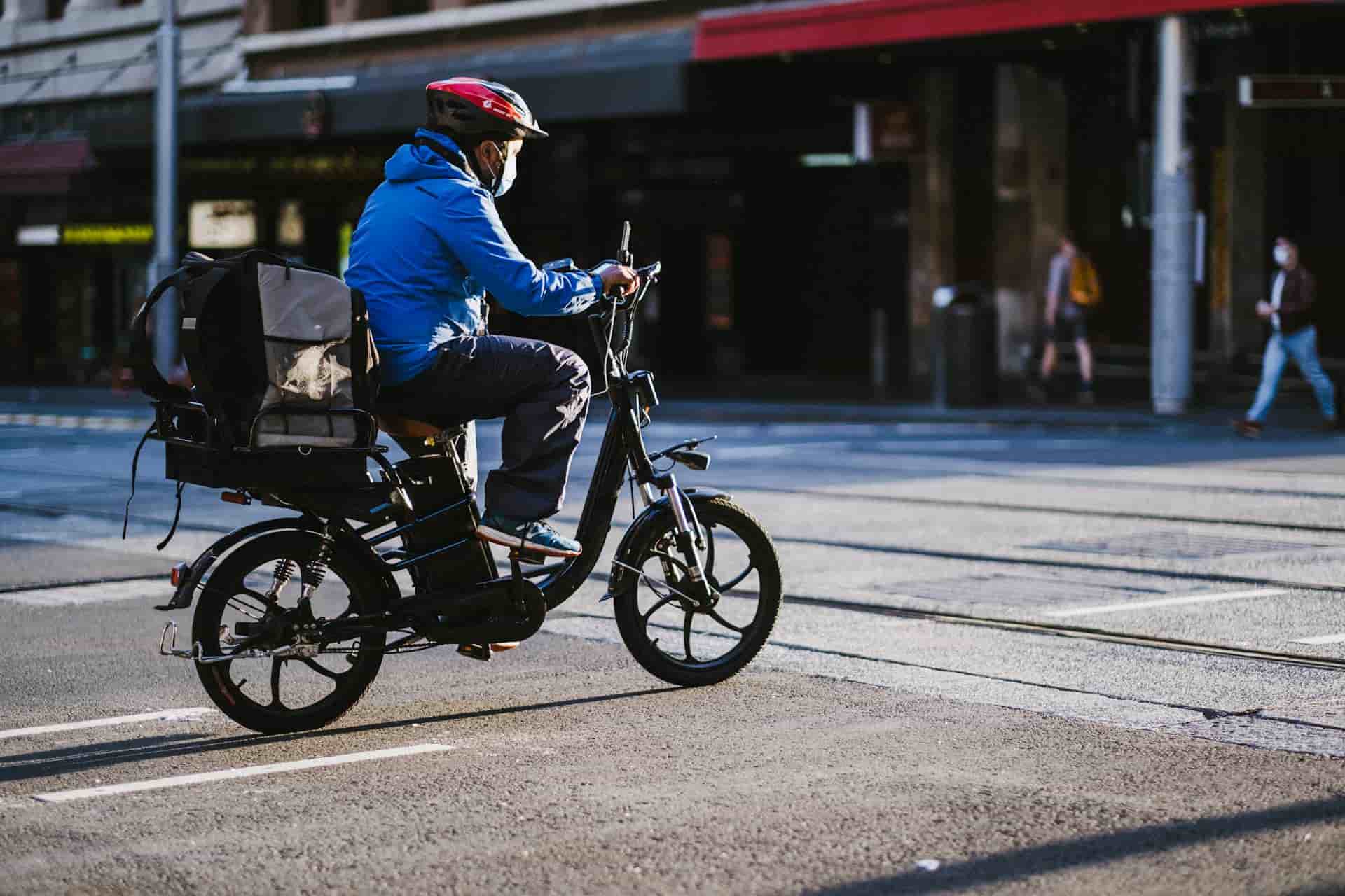 A courier riding an EV bike which is now possible for them to travel farther because e-bike charging networks