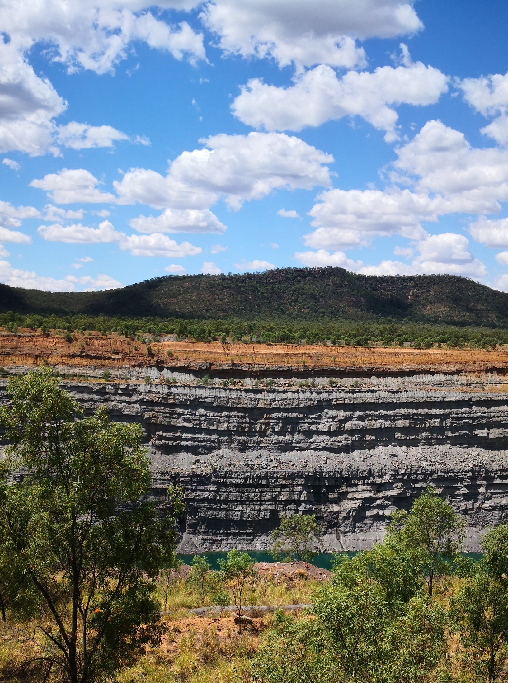 Blue sky, Qld landscape, wall of a coal mine pit, trees